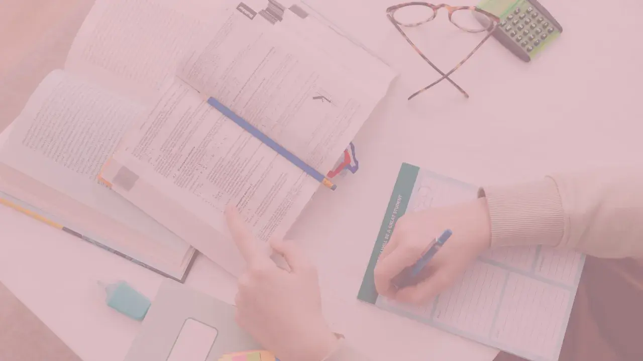 Uczniowie studiują, a na biurku leżą książki, okulary i kalkulator. Czy oceny na studiach mają znaczenie?