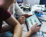 Dzieci programują robota na tablecie, ucząc się, czym zajmuje się informatyk.