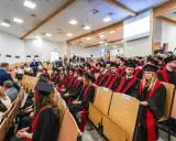 Absolwenci w togach siedzą na uroczystości w sali wykładowej. To ważny dzień dla studentów z Radomia.