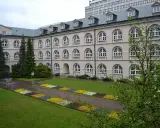 Dziedziniec z klombami i rzeźbą, idealne miejsce na studia prywatne.