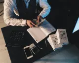 Agent ubezpieczeniowy liczy pieniądze, obok leżą telefony i notatnik. Zastanawiasz się, ile zarabia agent ubezpieczeniowy?