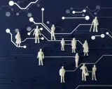 Figurki ludzi na tle obwodów drukowanych symbolizują zarządzanie i socjologię w biznesie i mediach, ukazując złożoność relacji i przepływ informacji.
