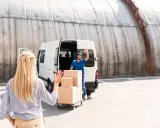 Kobieta macha do kuriera, który właśnie zakończył studia transportowe i dostarcza paczki.