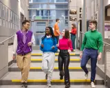 Studenci na schodach w nowoczesnym budynku Uniwersytetu Dolnośląskiego.