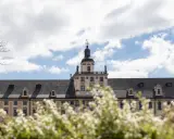 Majestatyczny gmach, idealne miejsce na studia we Wrocławiu. Wiosna kwitnie, a chmury na niebie zapraszają do nauki.
