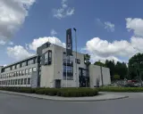 Nowoczesny budynek Uniwersytetu SWPS, jednej z uczelni w Krakowie, z flagą i parkingiem.