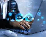 DevOps in action: osoba pracuje przy laptopie, na ekranie symbol nieskończoności z napisami DEV i OPS, otoczony ikonami technologicznymi.