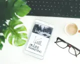 Biurko z tabletem pokazującym wykresy i hasło "online MARKETING", obok klawiatura, kawa i okulary. Idealne do social media studia.