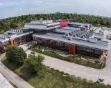 Nowoczesne budynki uczelni w Łodzi, otoczone zielenią, z widokiem na miasto.