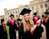 Uśmiechnięci absolwenci w togach z dyplomami. To piękny moment, by zacząć studia, gdy ma się 18 lat.