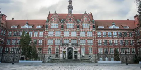 Imponujący budynek Politechniki Gdańskiej, jednej z ważnych uczelni Gdańsk, z charakterystyczną wieżą zegarową i ozdobną fasadą.