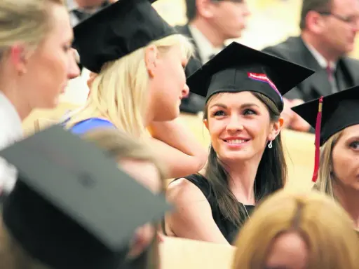 Grupa studentek w togach i biretach podczas uroczystości.