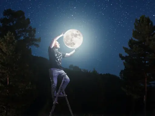 Mężczyzna na drabinie trzyma księżyc, marząc o studiach z astronomii. Nocne niebo pełne gwiazd.