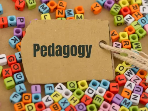 Kolorowe koraliki z literami tworzą tło dla brązowej metki z napisem "Pedagogy". Idealne do nauki i studiów online pedagogika.