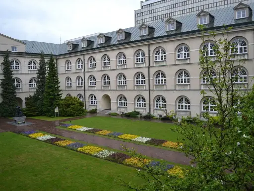 Dziedziniec z klombami i rzeźbą, idealne miejsce na studia prywatne.
