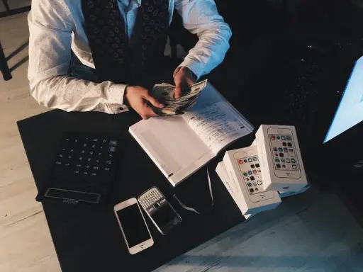Agent ubezpieczeniowy liczy pieniądze, obok leżą telefony i notatnik. Zastanawiasz się, ile zarabia agent ubezpieczeniowy?