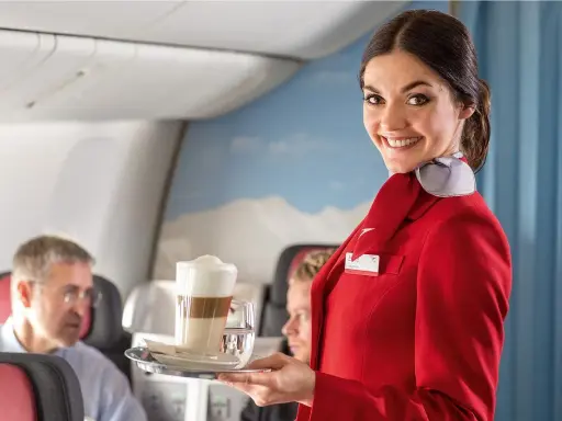 Uśmiechnięta stewardessa w czerwonym mundurku podaje kawę. Czy jej stewardessa zarobki są wysokie?