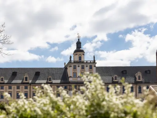 Majestatyczny gmach, idealne miejsce na studia we Wrocławiu. Wiosna kwitnie, a chmury na niebie zapraszają do nauki.