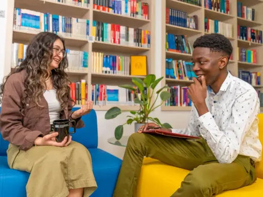 Dwoje studentów rozmawia w bibliotece. To może być początek ich przygody z psychologią dla magistrów w Warszawie.