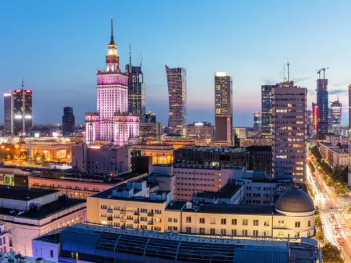 Warszawski krajobraz miejski nocą, z Pałacem Kultury i Nauki w centrum. Wiele nowoczesnych budynków, gdzie znajdują się uczelnie prywatne Warszawa.