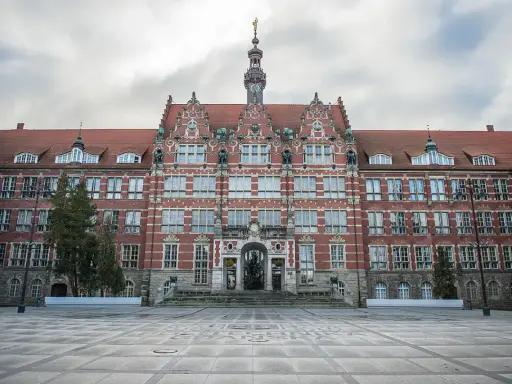 Imponujący budynek Politechniki Gdańskiej, jednej z ważnych uczelni Gdańsk, z charakterystyczną wieżą zegarową i ozdobną fasadą.