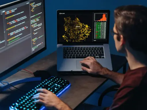 Młody big data engineer analizuje dane na ekranach, tworząc wizualizacje i pisząc kod.