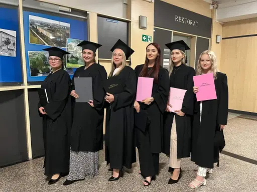 Absolwentki studiów w Raciborzu w togach i biretach z pracami licencjackimi.