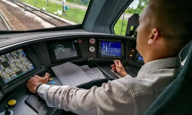 Maszynista w kabinie steruje pociągiem. Zastanawiasz się, ile zarabia maszynista? To odpowiedzialna praca.