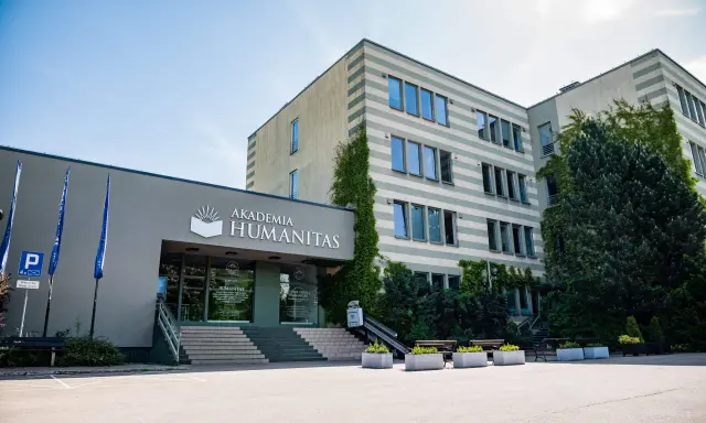 Akademia Humanitas w Katowicach, gdzie można studiować psychologię. Budynek z zielenią i parkingiem.
