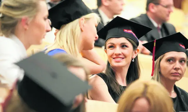 Grupa studentek w togach i biretach podczas uroczystości.