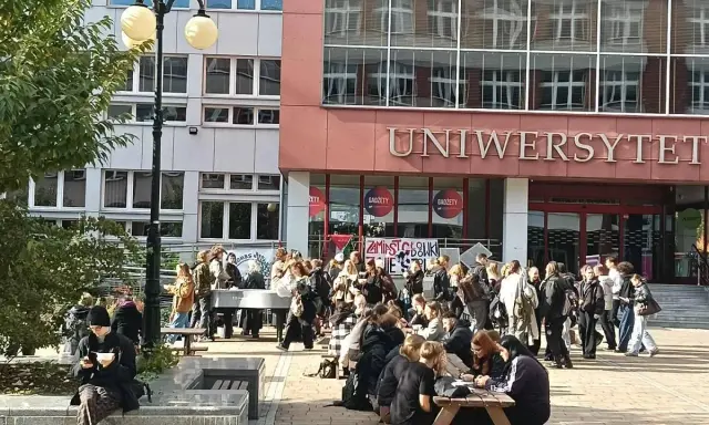 Grupa studentów przed budynkiem z napisem "UNIWERSYTET". Zastanawiasz się, czym się różni akademia od uniwersytetu?