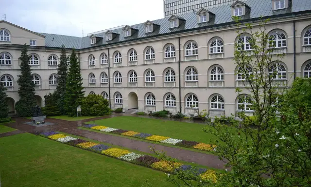 Dziedziniec z klombami i rzeźbą, idealne miejsce na studia prywatne.