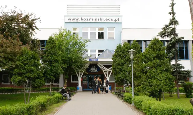 Studenci przed budynkiem koźmin uczelnia. W tle logo uczelni i napis www.kozminiński.edu.pl.