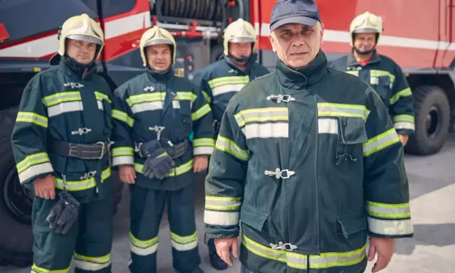 Strażacy w pełnym rynsztunku przy wozie strażackim. Zastanawiasz się, ile zarabia strażak?