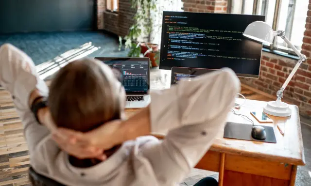 Praca po informatyce: programista zrelaksowany przed ekranem z kodem i danymi.