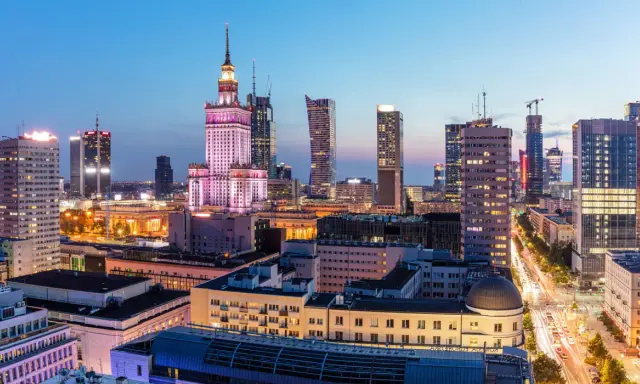Warszawski krajobraz miejski nocą, z Pałacem Kultury i Nauki w centrum. Wiele nowoczesnych budynków, gdzie znajdują się uczelnie prywatne Warszawa.