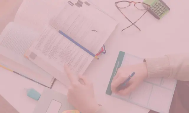 Uczniowie studiują, a na biurku leżą książki, okulary i kalkulator. Czy oceny na studiach mają znaczenie?