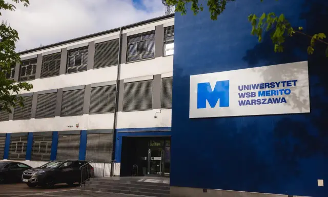 Nowoczesny budynek Uniwersytetu WSB Merito Warszawa z niebieskim logo.