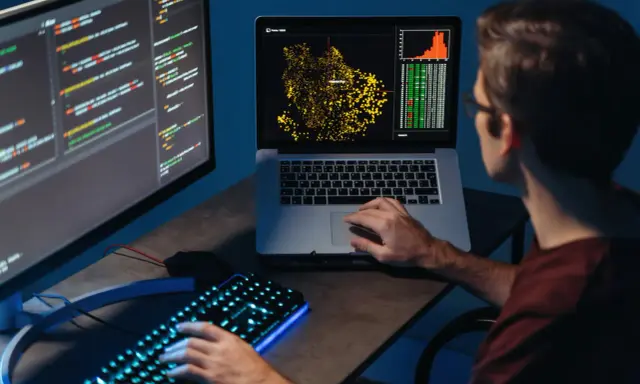 Młody big data engineer analizuje dane na ekranach, tworząc wizualizacje i pisząc kod.