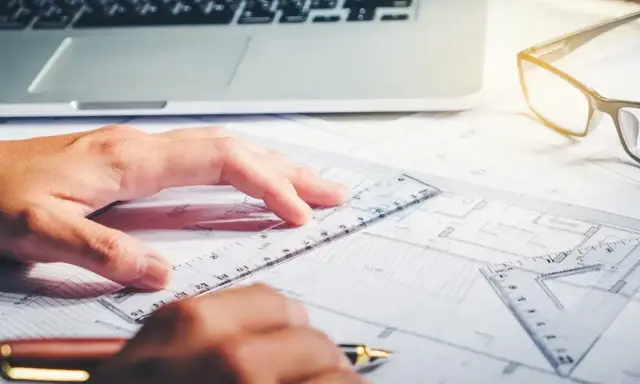 Rysowanie planów, laptop i okulary na biurku. Zastanawiasz się, ile zarabia architekt?