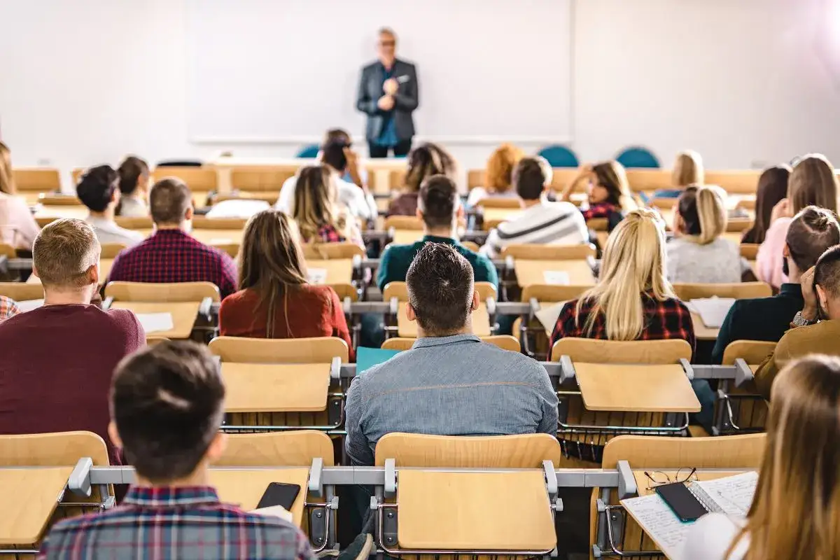 Adiunkt prowadzi wykład dla studentów siedzących w ławkach.