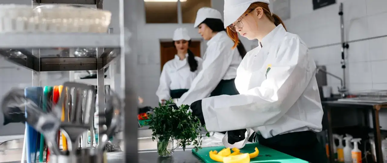 Uczą się, jak zostać kucharzem, ćwicząc krojenie warzyw i ziół w profesjonalnej kuchni.