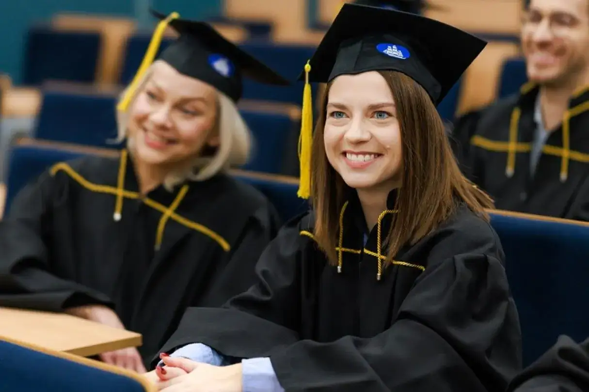 Uśmiechnięci absolwenci w togach, gotowi na nowy etap. Kozminski cennik czeka na przyszłych studentów.
