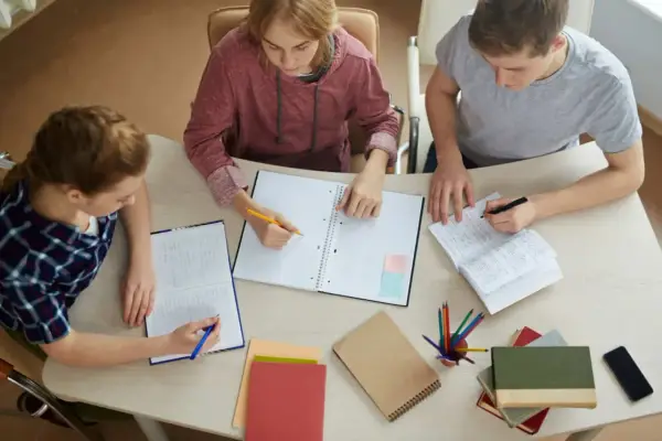 Trzech studentów pracuje nad pracą licencjacką, analizując metody badawcze.