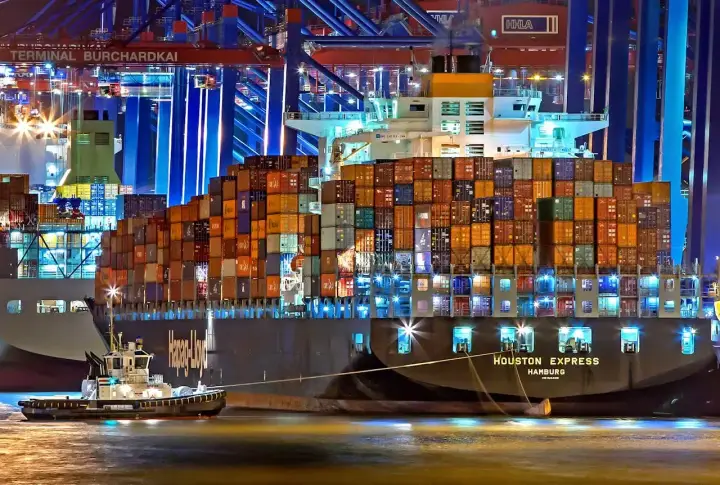 Nocą w porcie holownik pomaga wielkiemu kontenerowcowi. Spedytor, kto to? To osoba organizująca transport.